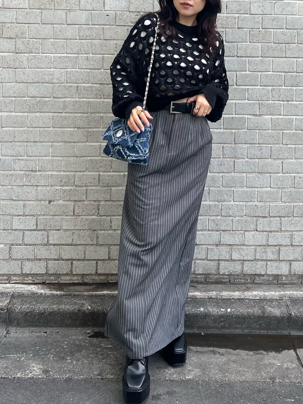 グレー系のスカート、ブラック系のニット/セーター、ブルー系のショルダーバッグを着用したレディースの冬コーディネートの2枚目の写真