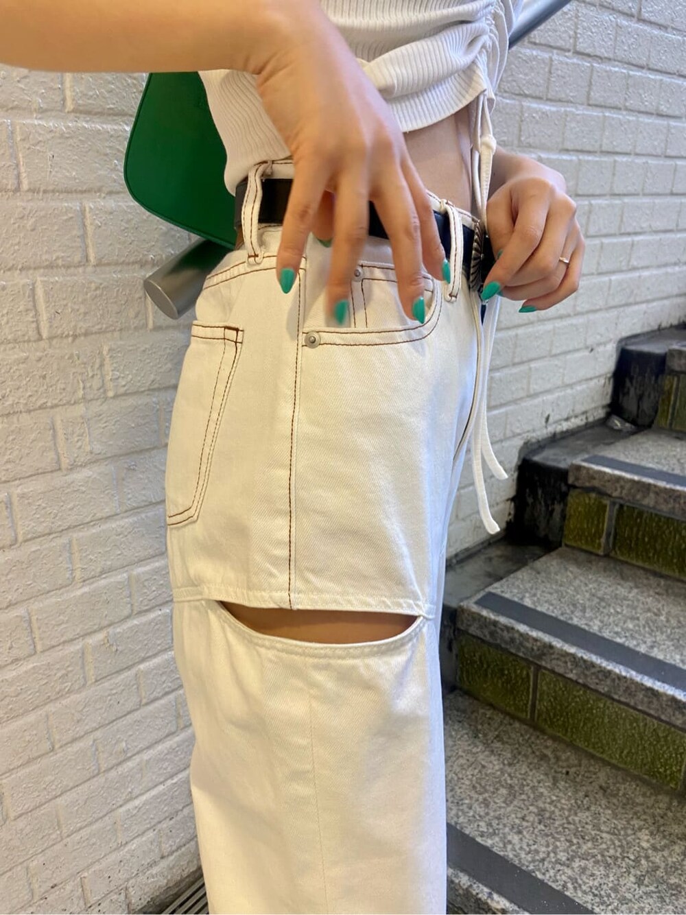 ホワイト系のデニムパンツ、ブラック系のサンダル、グリーン系のショルダーバッグを着用したレディースの春コーディネートの6枚目の写真