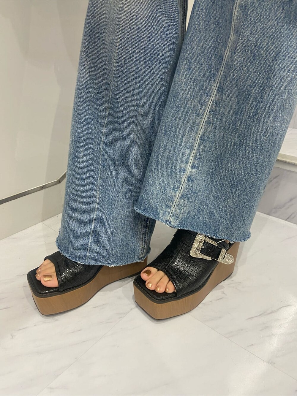 ブラック系のショルダーバッグ、ブラック系のサンダル、ブルー系のデニムパンツを着用したレディースの夏コーディネートの8枚目の写真