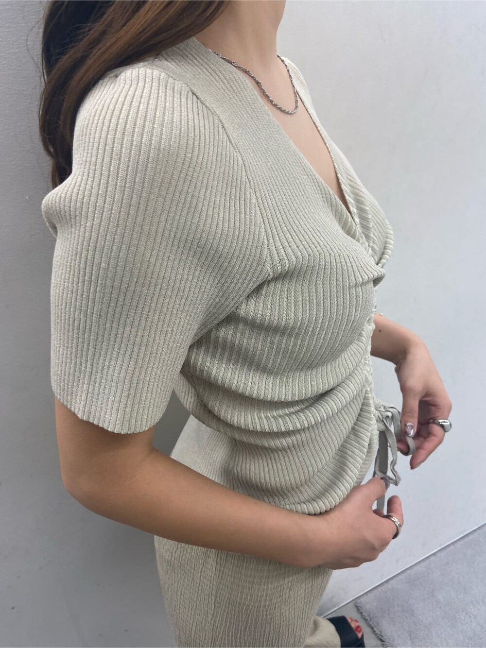 ホワイト系のニット/セーター、ブラック系のサンダル、ブラック系のハンドバッグを着用したレディースの夏コーディネートの2枚目の写真