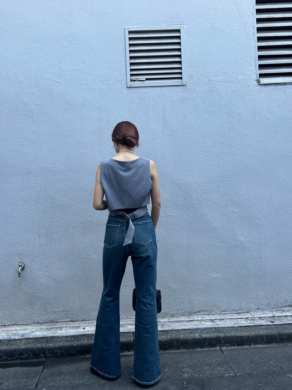 ブルー系のデニムパンツ、グレー系のシャツ/ブラウス、ブラック系のショルダーバッグを着用したレディースの夏コーディネートの5枚目の写真