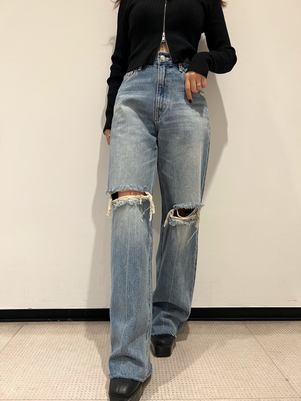 ブルー系のデニムパンツ、ブラック系のニット/セーター、ブラック系のブーツを着用したレディースの秋コーディネートの7枚目の写真