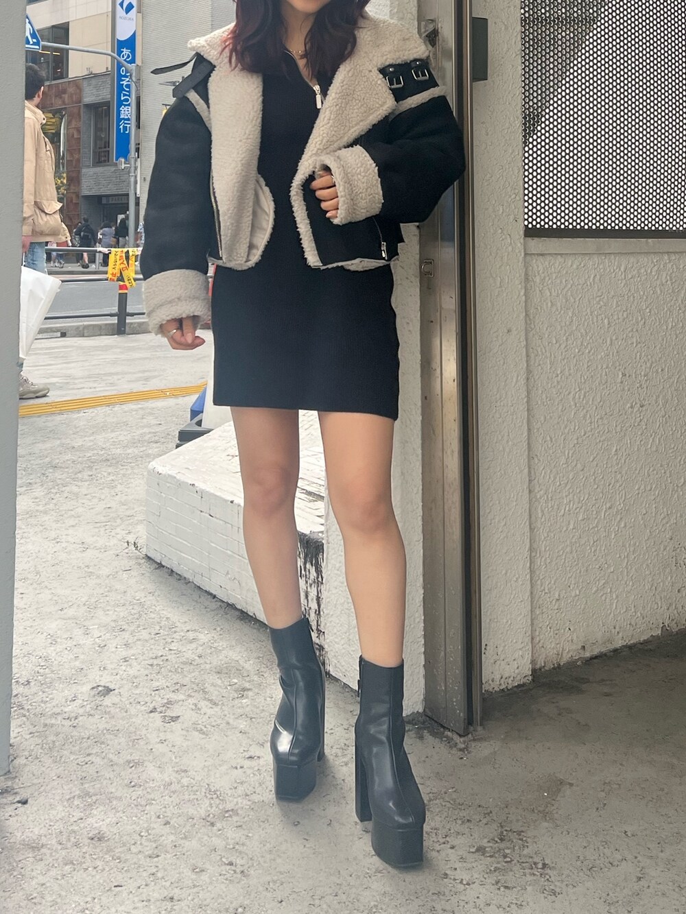 ブラック系のブーツ、ブラック系のムートンコート、ブラック系のワンピースを着用したレディースの秋コーディネートの4枚目の写真