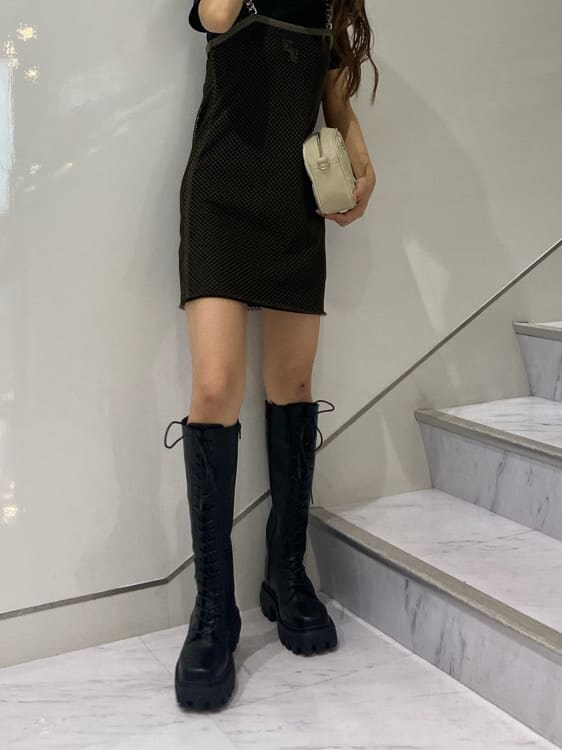 ブラック系のブーツ、ホワイト系のショルダーバッグ、ブラック系のワンピースを着用したレディースの夏コーディネートの2枚目の写真