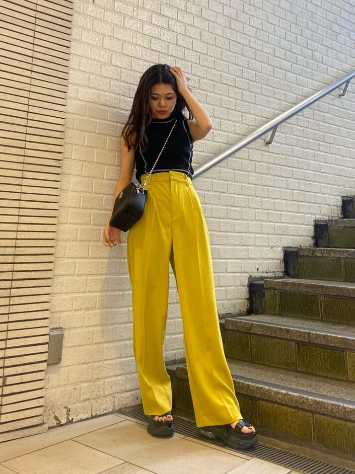 イエロー系のスラックス、ブラック系のショルダーバッグ、ブラック系のサンダルを着用したレディースの春コーディネートの2枚目の写真