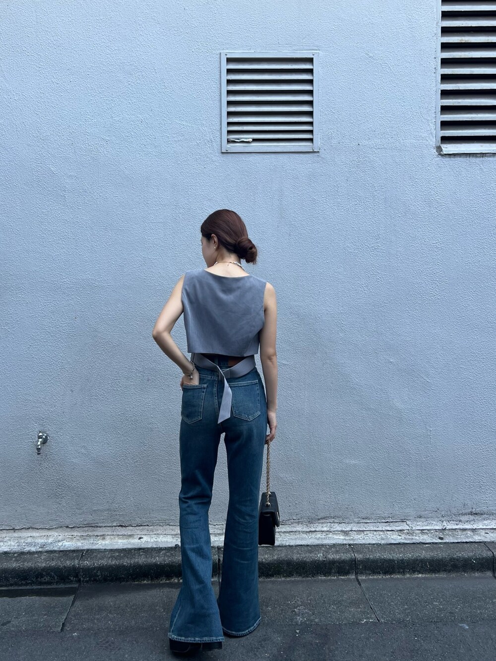 ブルー系のデニムパンツ、グレー系のシャツ/ブラウス、ブラック系のショルダーバッグを着用したレディースの夏コーディネートの4枚目の写真