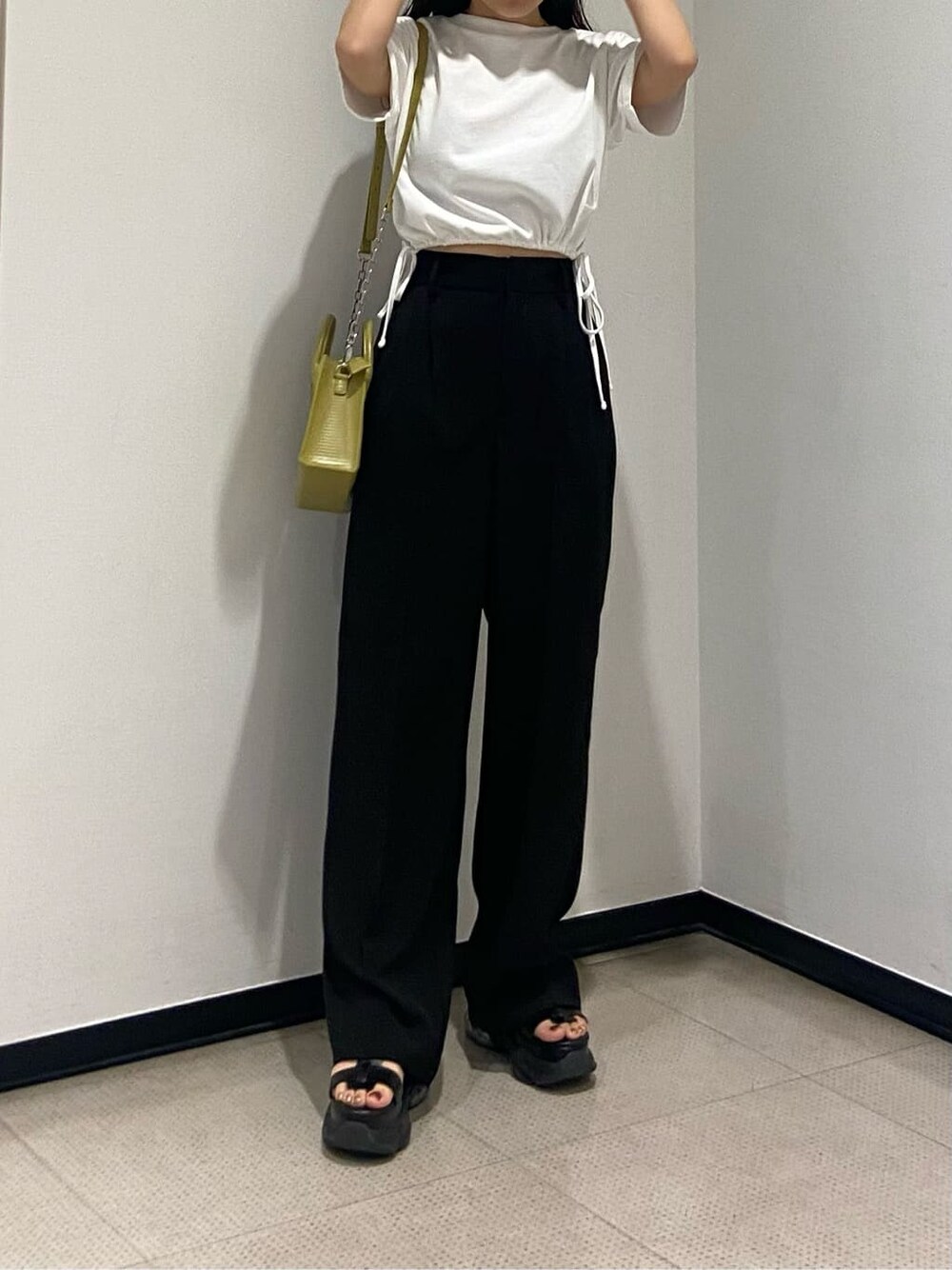 ブラック系のスラックス、ホワイト系のTシャツ/カットソー、イエロー系のショルダーバッグを着用したレディースの春コーディネートの3枚目の写真