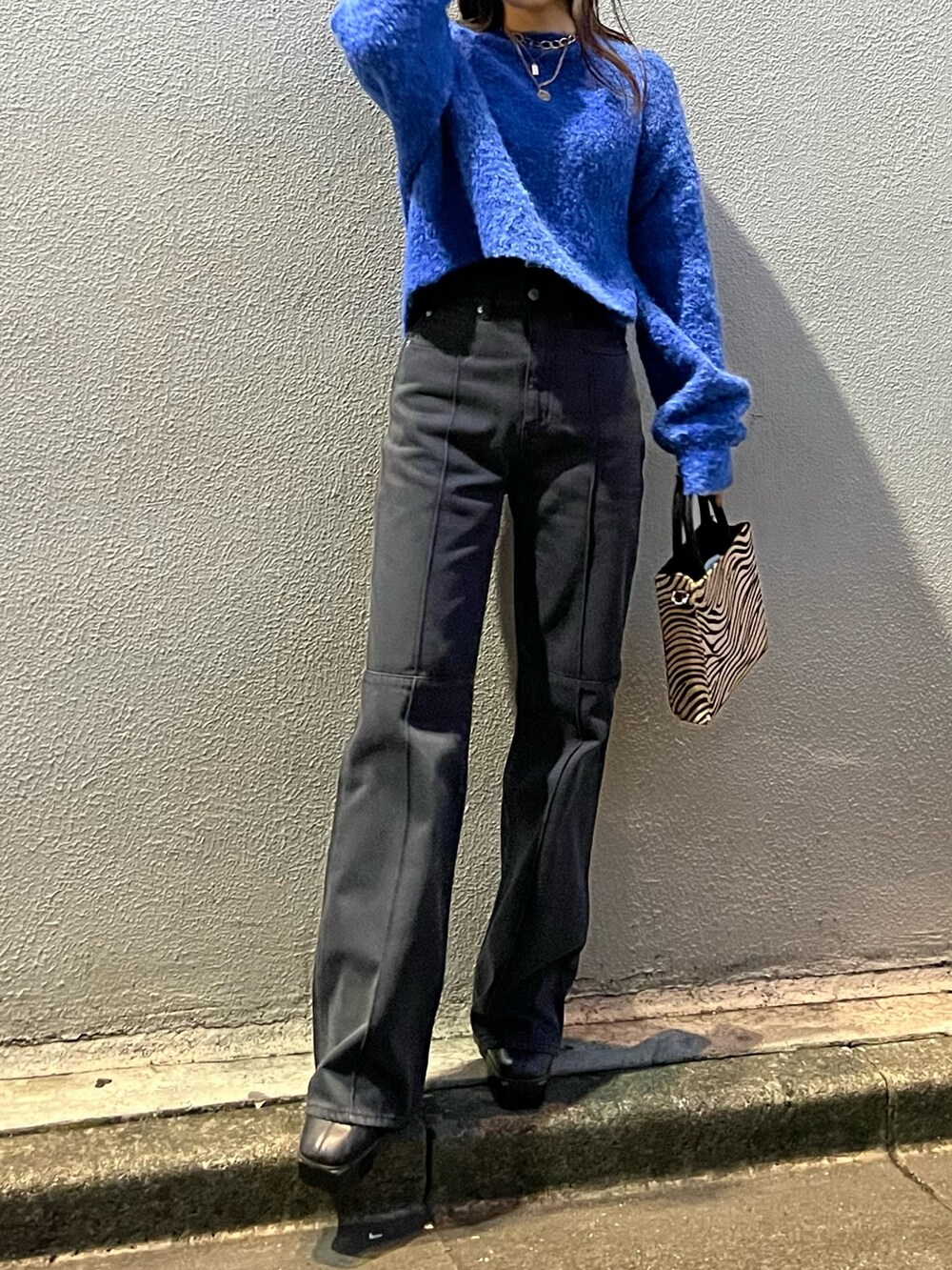 ブルー系のニット/セーター、その他のショルダーバッグ、ブラック系のデニムパンツを着用したレディースの冬コーディネートの2枚目の写真