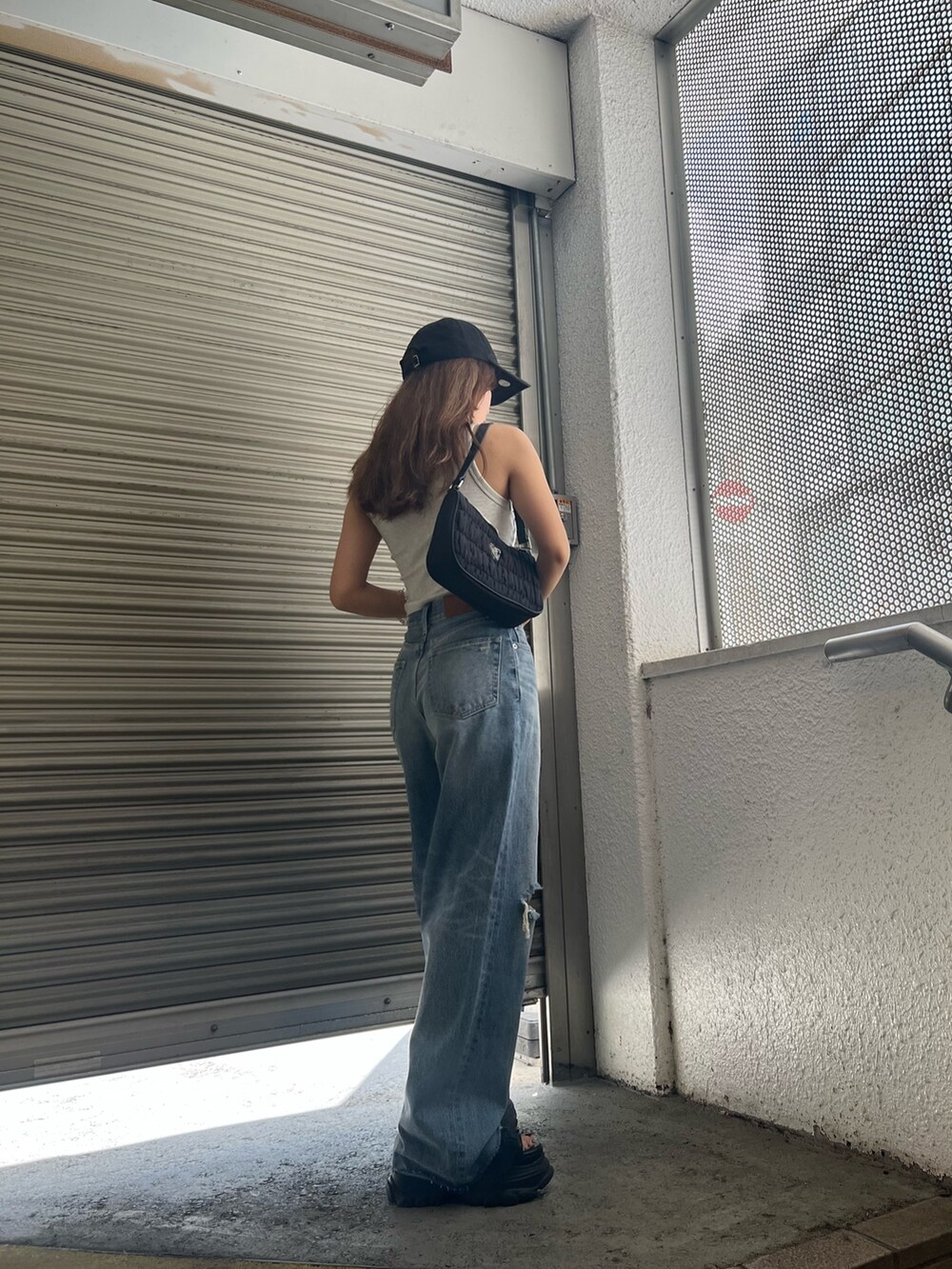 ブラック系のサンダル、ブルー系のデニムパンツ、グレー系のタンクトップを着用したレディースの夏コーディネートの4枚目の写真