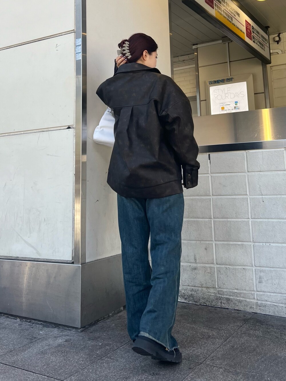 ブルー系のデニムパンツ、ホワイト系のハンドバッグ、ブラック系のブーツを着用したレディースの冬コーディネートの5枚目の写真