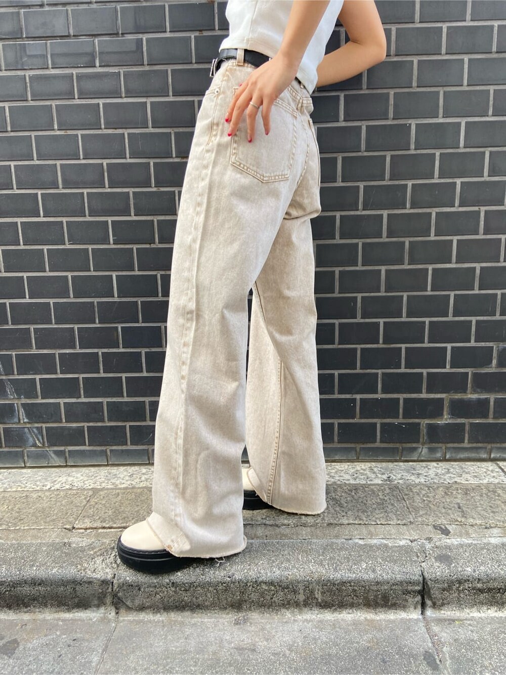 ブラック系のボストンバッグ、ベージュ系のTシャツ/カットソー、ベージュ系のデニムパンツを着用したレディースの春コーディネートの6枚目の写真