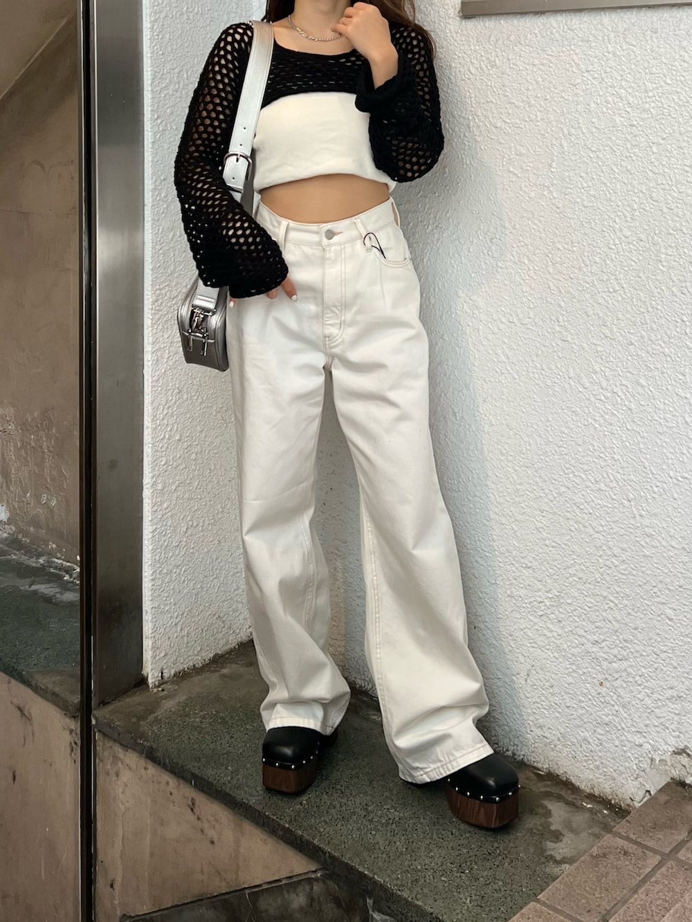 ホワイト系のデニムパンツ、ブラック系のサンダル、ブラック系のニット/セーターを着用したレディースの春コーディネートの4枚目の写真