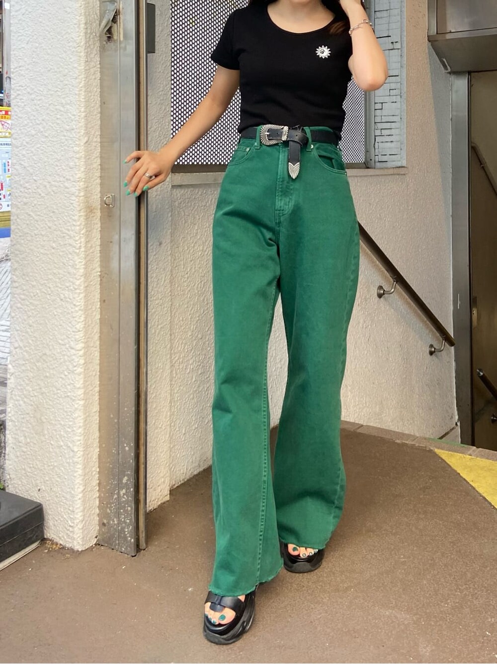 ブラック系のTシャツ/カットソー、グリーン系のデニムパンツ、ブラック系のサンダルを着用したレディースの春コーディネートの3枚目の写真