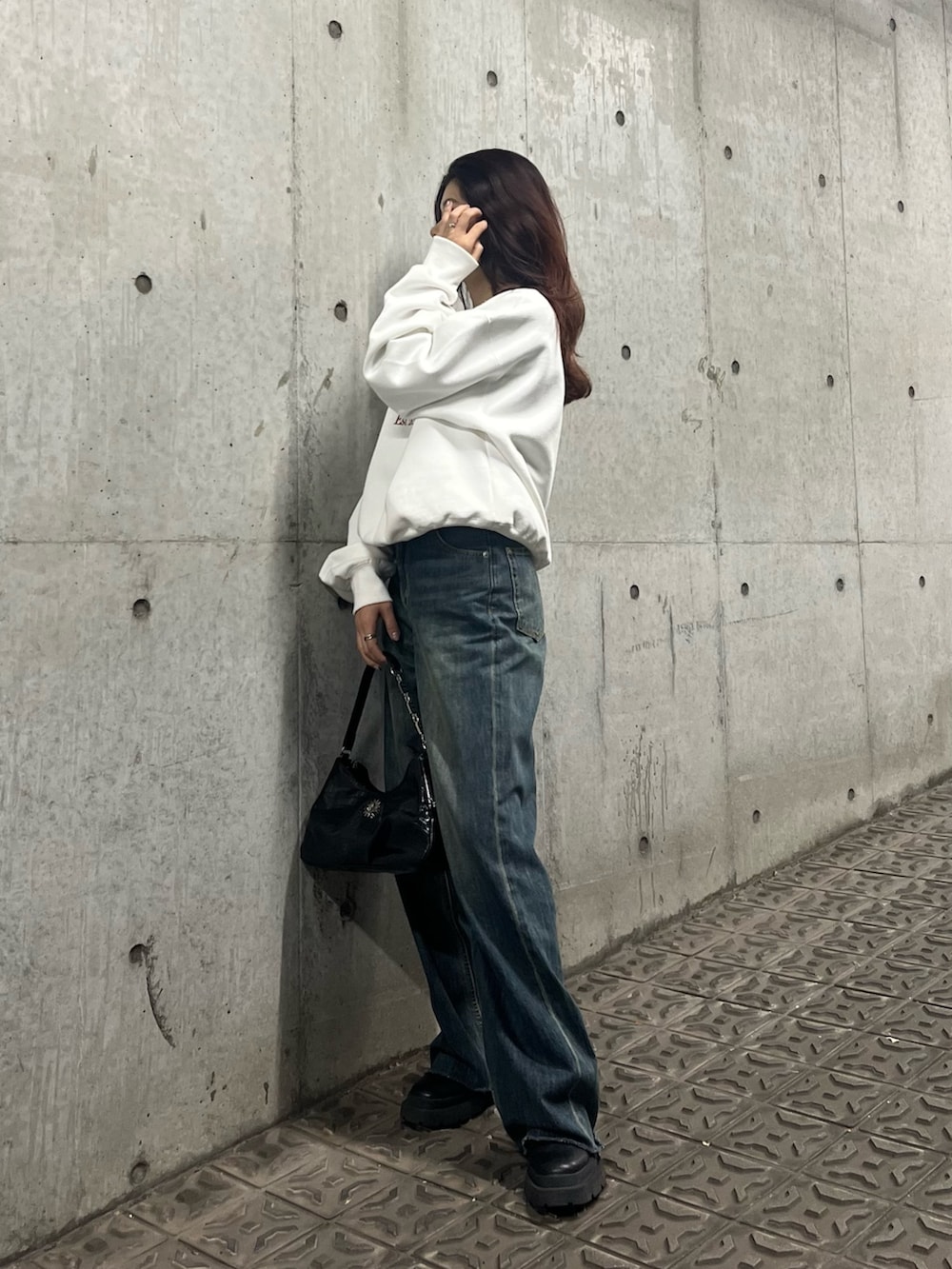 ブルー系のデニムパンツ、ブラック系のブーツ、ブラック系のハンドバッグを着用したレディースの冬コーディネートの4枚目の写真