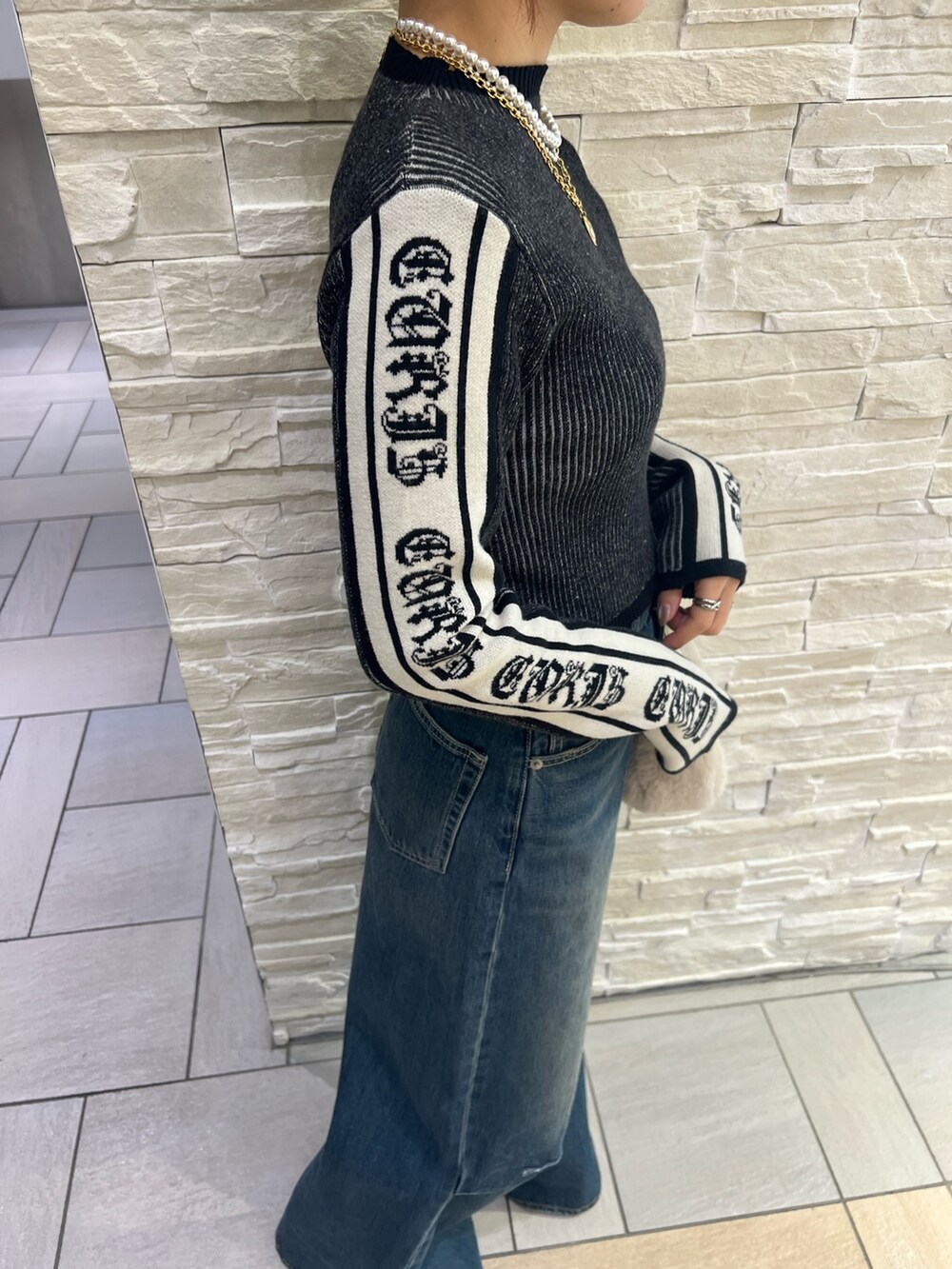 ブルー系のデニムパンツ、ホワイト系のショルダーバッグ、ブラック系のニット/セーターを着用したレディースの冬コーディネートの6枚目の写真