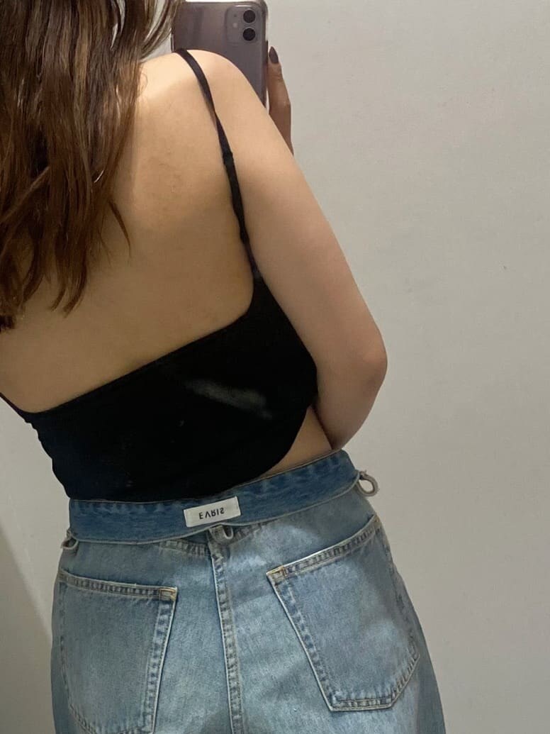 ブラック系のキャミソール、ホワイト系のサンダル、ブルー系のデニムパンツを着用したレディースの夏コーディネートの6枚目の写真
