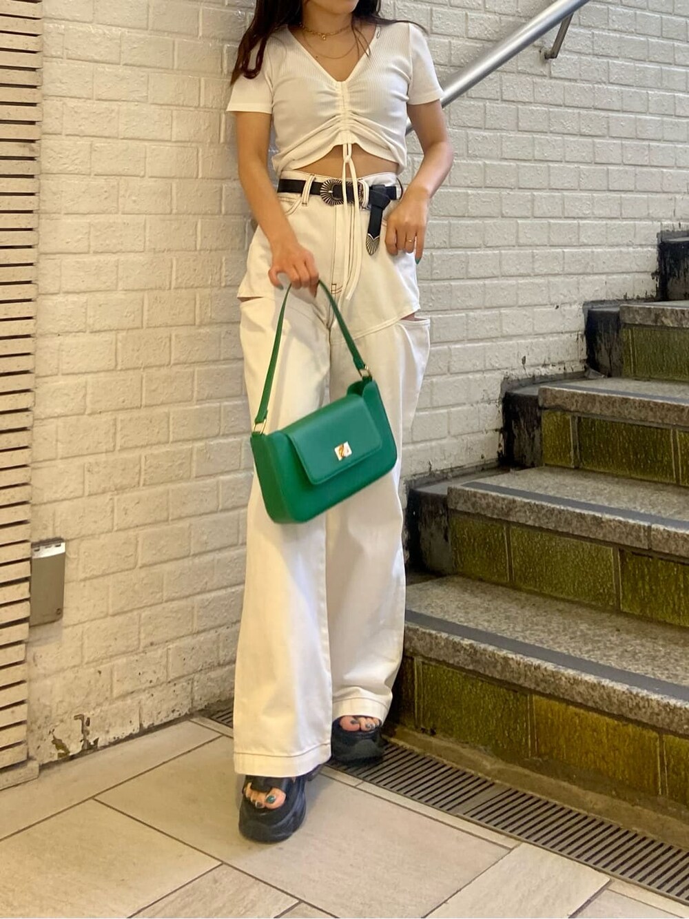 ホワイト系のデニムパンツ、ブラック系のサンダル、グリーン系のショルダーバッグを着用したレディースの春コーディネートの3枚目の写真