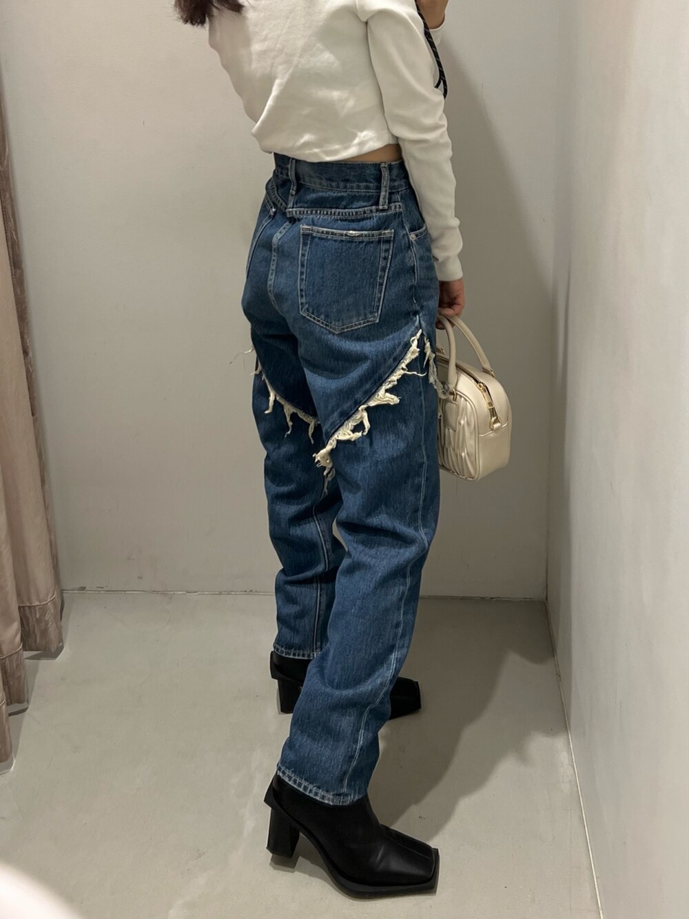 ブルー系のデニムパンツ、ホワイト系のショルダーバッグ、ホワイト系のTシャツ/カットソーを着用したレディースの秋コーディネートの6枚目の写真