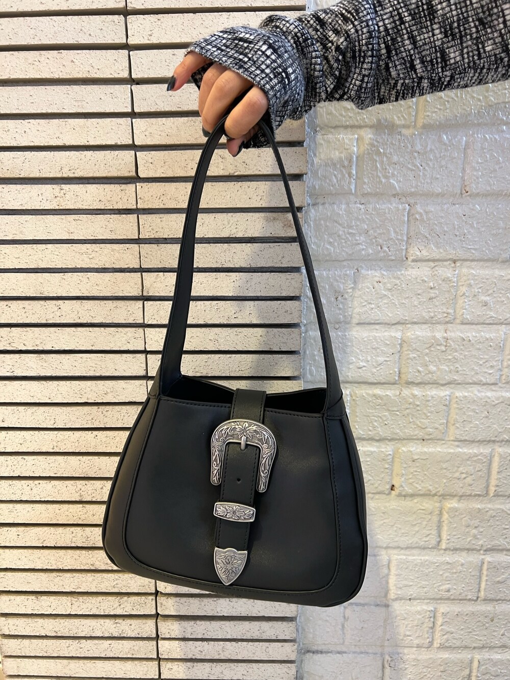 ブルー系のデニムパンツ、ブラック系のハンドバッグ、ブラック系のニット/セーターを着用したレディースの冬コーディネートの7枚目の写真