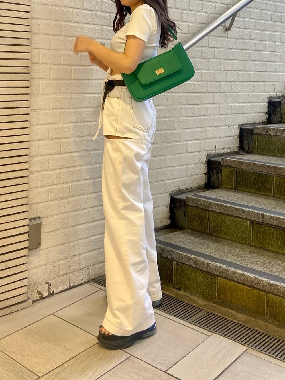 ホワイト系のデニムパンツ、ブラック系のサンダル、グリーン系のショルダーバッグを着用したレディースの春コーディネートの4枚目の写真