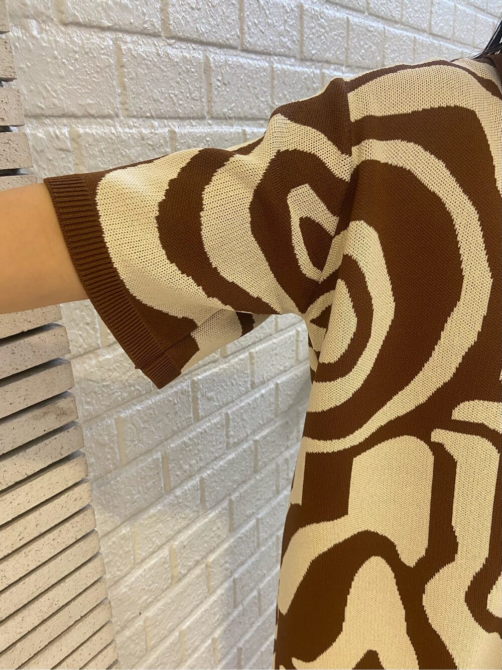 ホワイト系のスニーカー、ブラック系のキャミソール、ブラウン系のニット/セーターを着用したレディースの春コーディネートの5枚目の写真