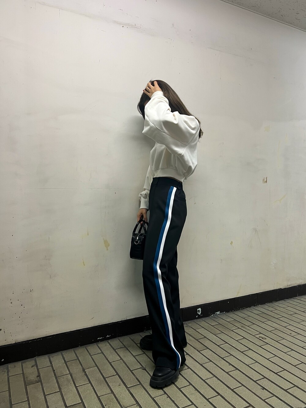 ブラック系のスラックス、ブラック系のショルダーバッグ、ホワイト系のスウェットを着用したレディースの冬コーディネートの3枚目の写真