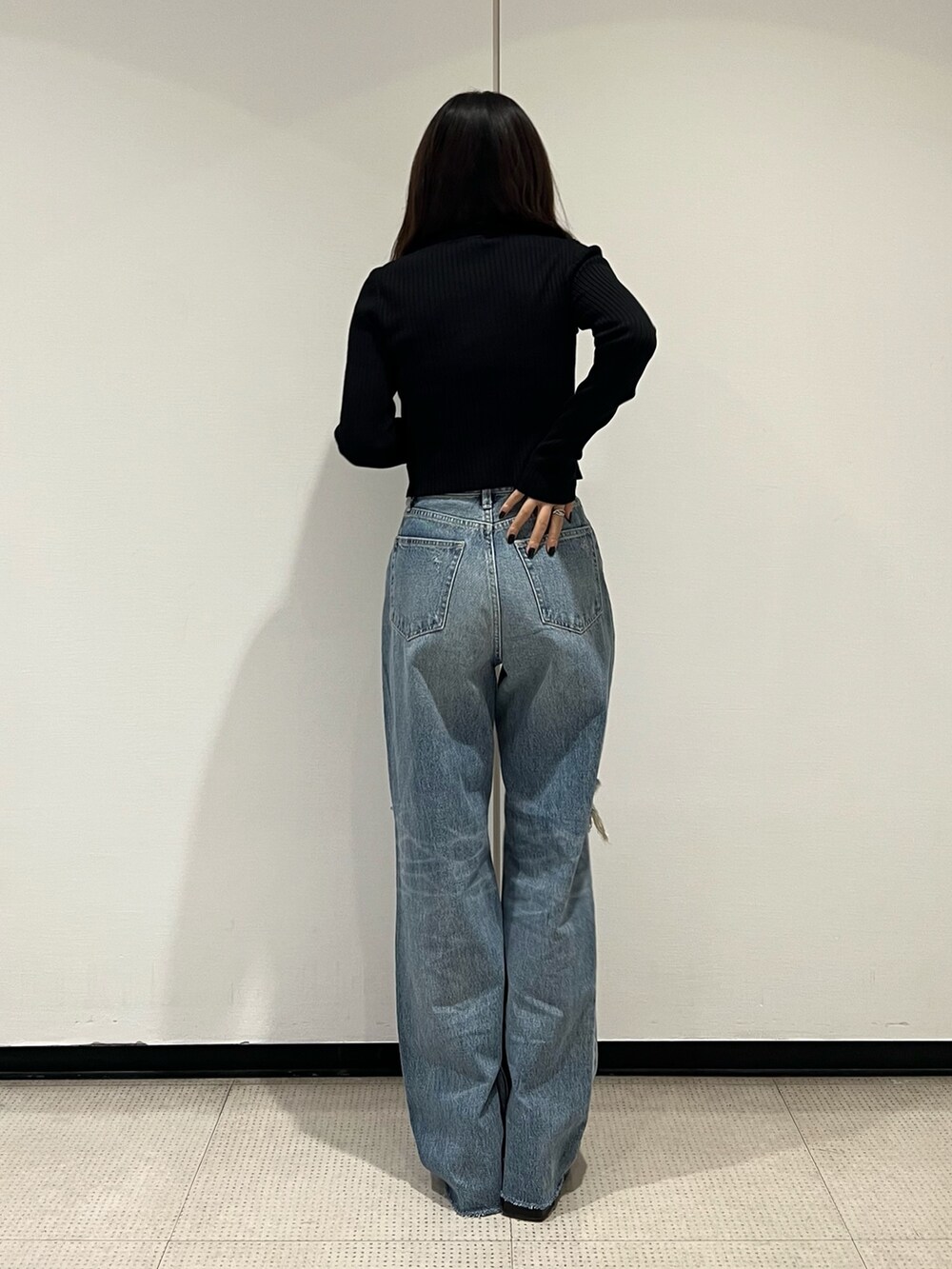 ブルー系のデニムパンツ、ブラック系のニット/セーター、ブラック系のブーツを着用したレディースの秋コーディネートの4枚目の写真