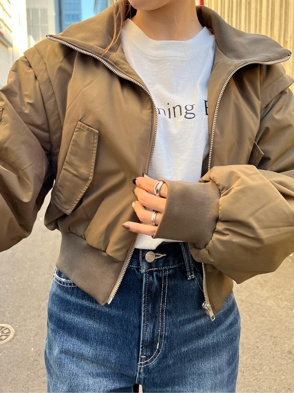 ブラック系のブーツ、ホワイト系のTシャツ/カットソー、ベージュ系のMA-1を着用したレディースの秋コーディネートの6枚目の写真