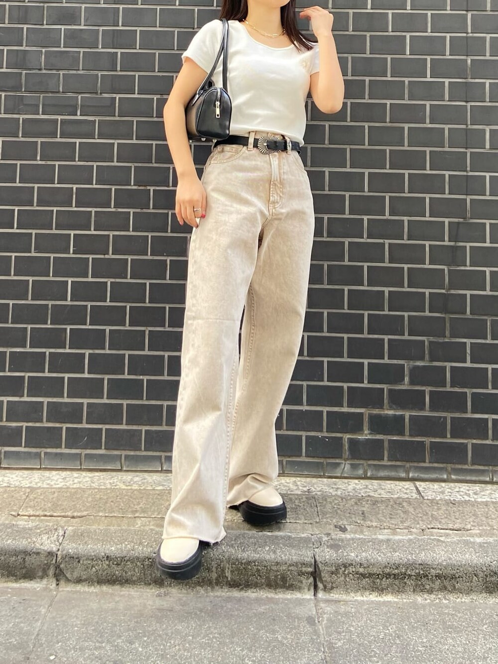 ブラック系のボストンバッグ、ベージュ系のTシャツ/カットソー、ベージュ系のデニムパンツを着用したレディースの春コーディネートの3枚目の写真