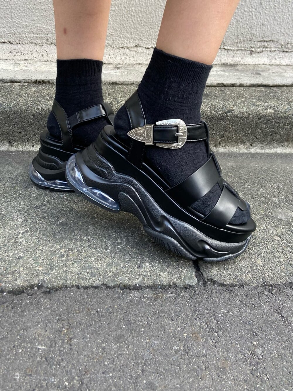 ブラック系のショルダーバッグ、ブラック系のTシャツ/カットソー、ベージュ系のスカートを着用したレディースの春コーディネートの8枚目の写真