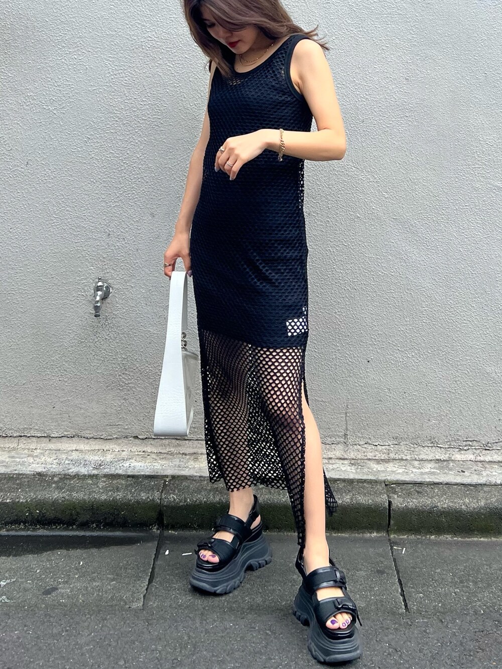 ブラック系のワンピース、ブラック系のサンダル、ホワイト系のハンドバッグを着用したレディースの夏コーディネートの2枚目の写真
