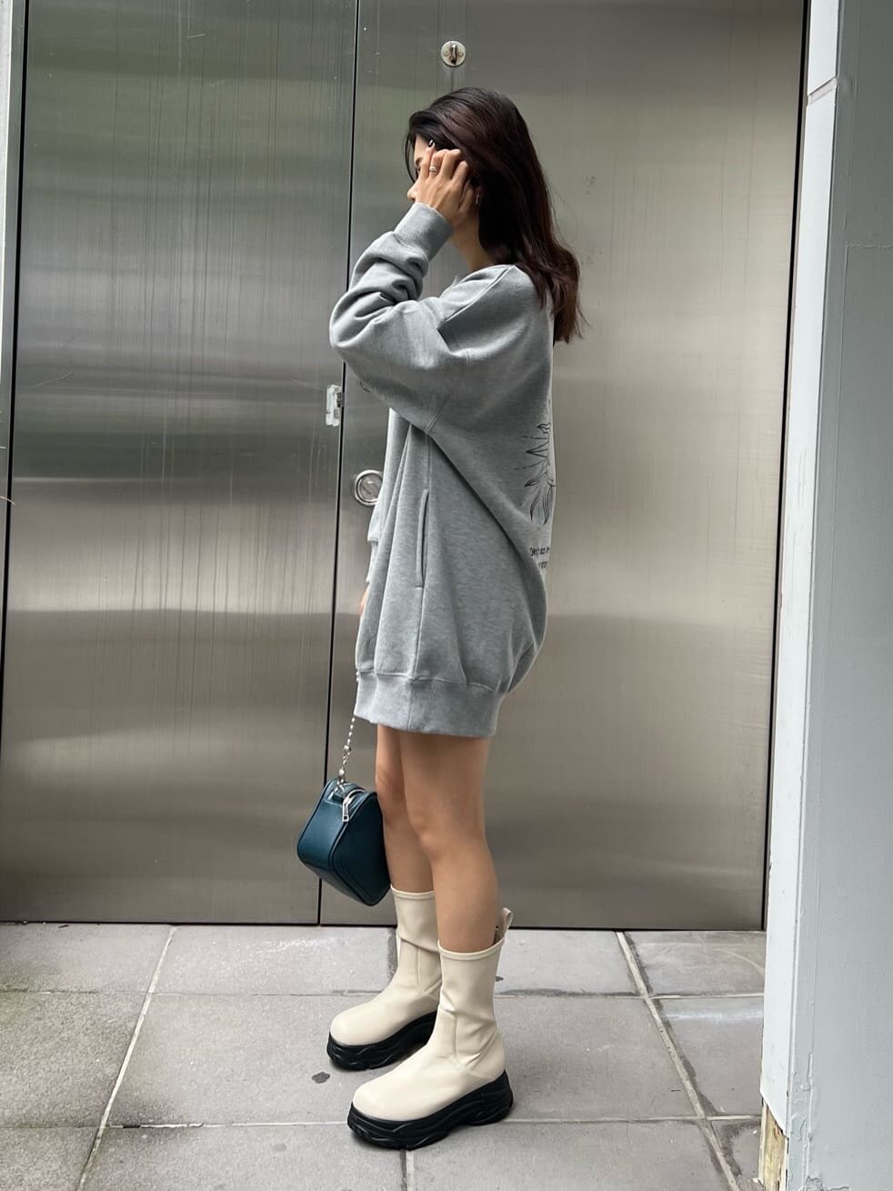 グリーン系のショルダーバッグ、グレー系のスウェット、ホワイト系のブーツを着用したレディースの秋コーディネートの2枚目の写真