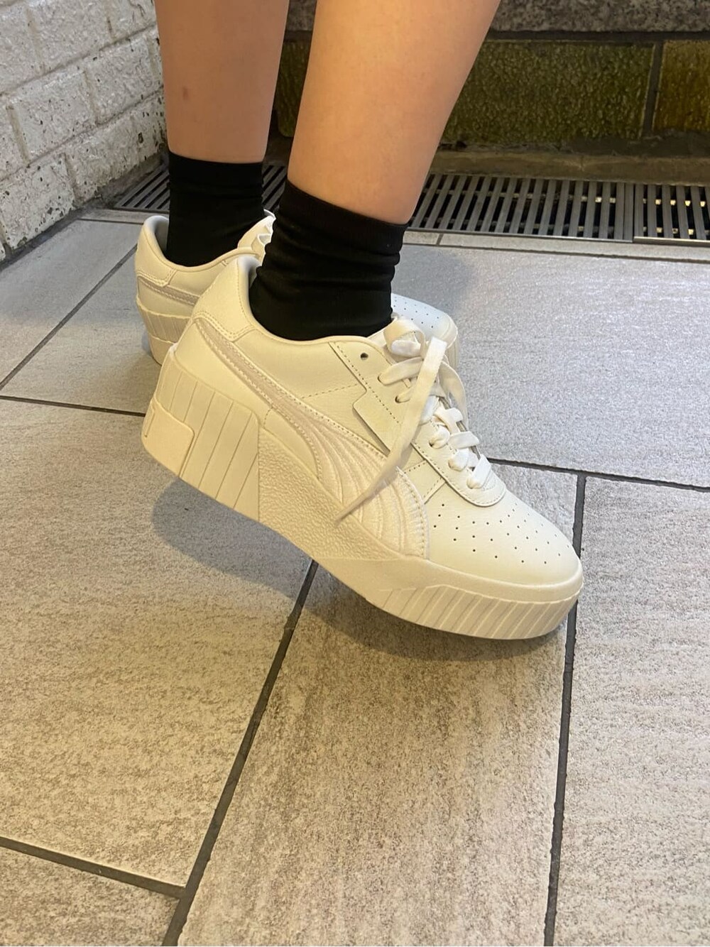 ホワイト系のスニーカー、ブラック系のキャミソール、ブラウン系のニット/セーターを着用したレディースの春コーディネートの7枚目の写真