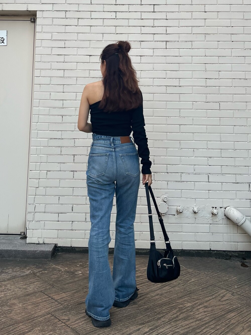 ブラック系のTシャツ/カットソー、ブラック系のサンダル、ブルー系のデニムパンツを着用したレディースの夏コーディネートの5枚目の写真