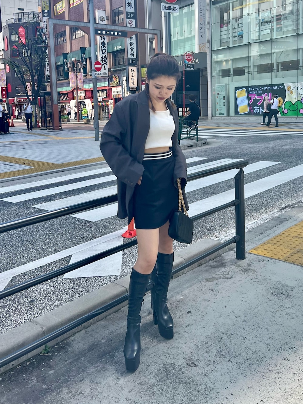 ブラック系のブーツ、ブラック系のショルダーバッグ、ブラック系のスカートを着用したレディースの秋コーディネートの2枚目の写真