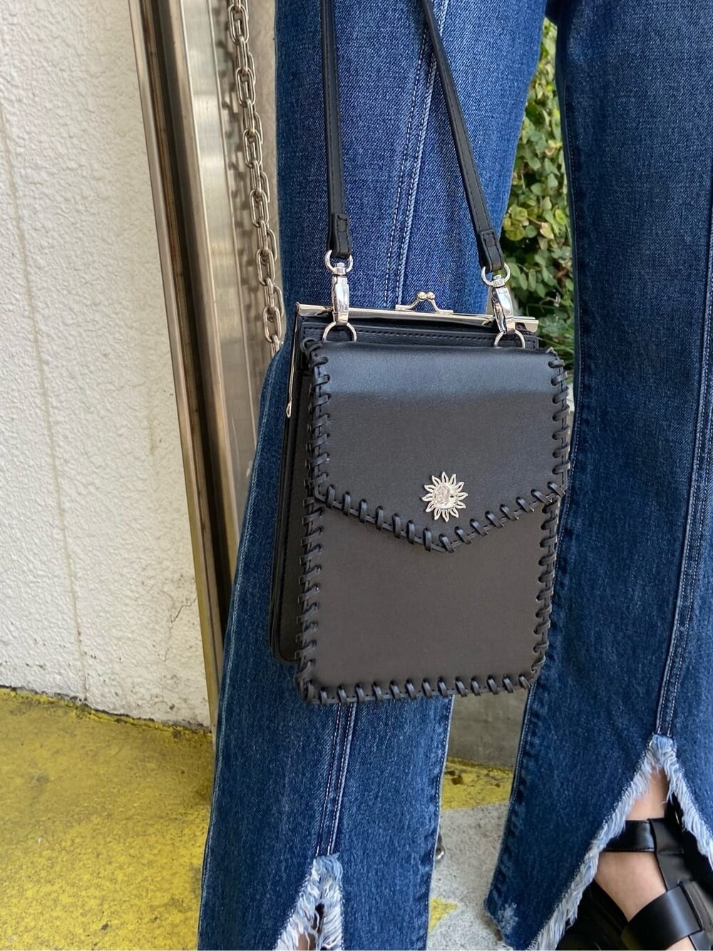 ブラック系のショルダーバッグ、ホワイト系のTシャツ/カットソー、ブルー系のデニムパンツを着用したレディースの春コーディネートの7枚目の写真