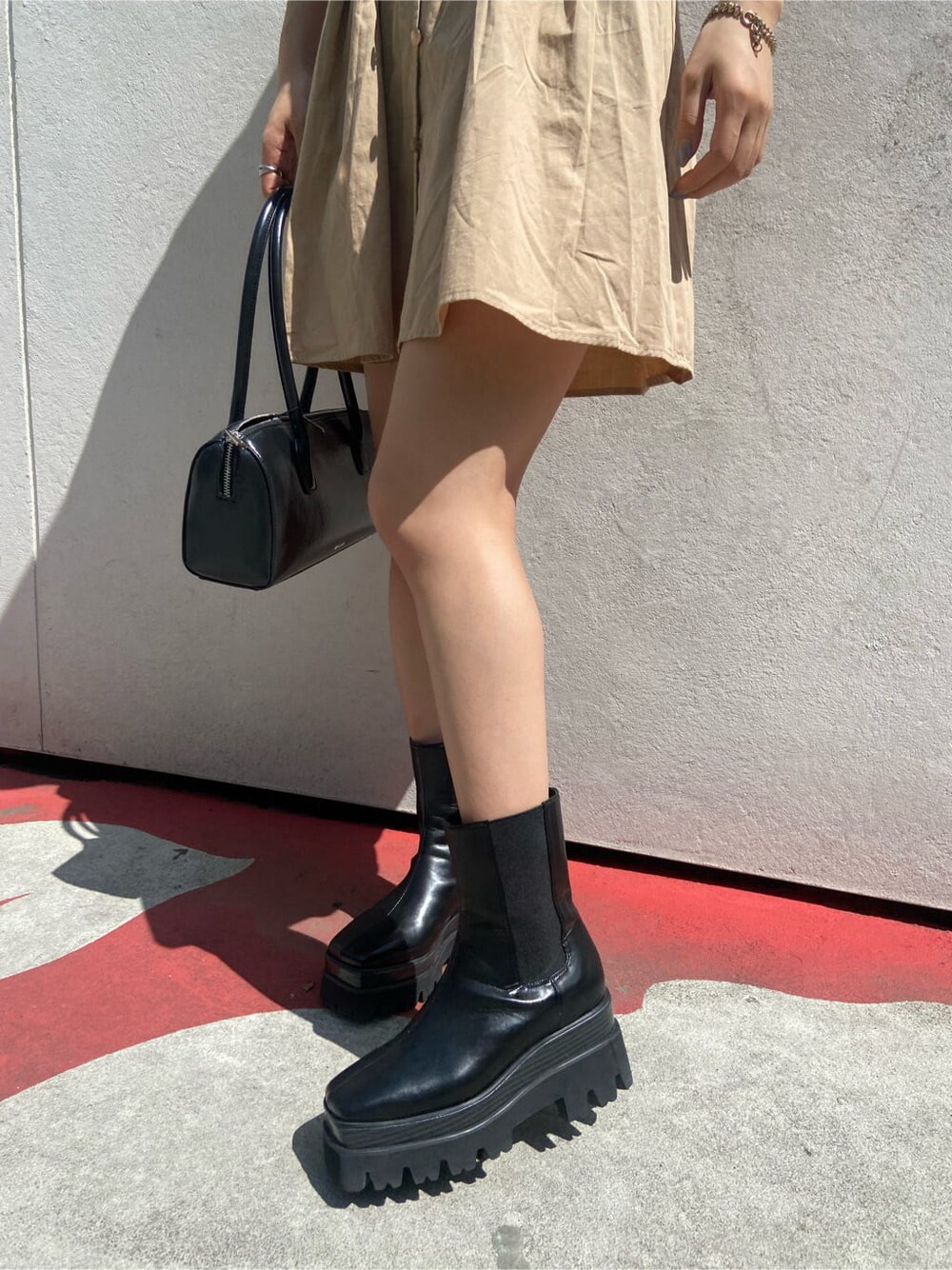 ブラック系のボストンバッグ、ブラック系のブーツ、ベージュ系のワンピースを着用したレディースの春コーディネートの7枚目の写真