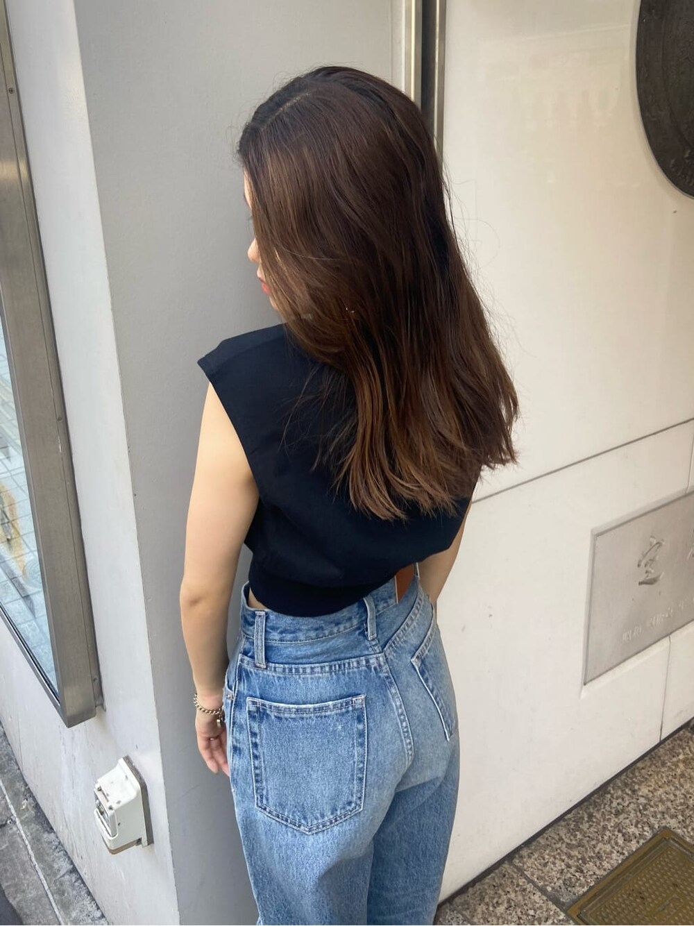 ブラック系のサンダル、ブラック系のTシャツ/カットソー、ブルー系のデニムパンツを着用したレディースの夏コーディネートの6枚目の写真