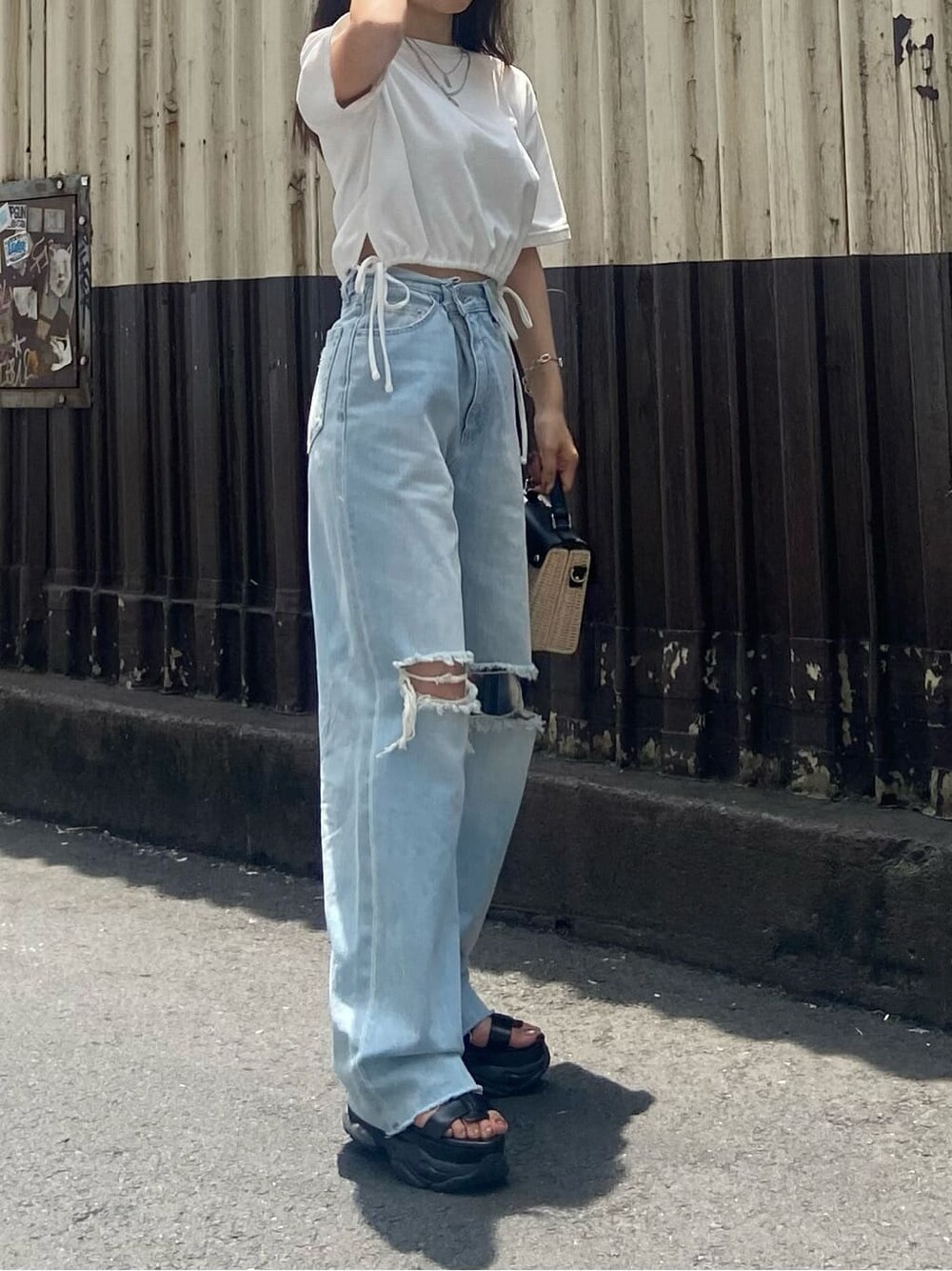 ブラック系のサンダル、ホワイト系のTシャツ/カットソー、ブルー系のデニムパンツを着用したレディースの夏コーディネートの3枚目の写真