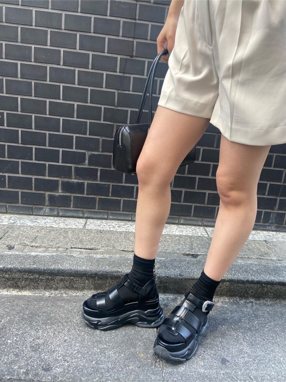 ブラック系のボストンバッグ、ブラック系のキャミソール、ホワイト系のつなぎ/オールインワンを着用したレディースの春コーディネートの6枚目の写真