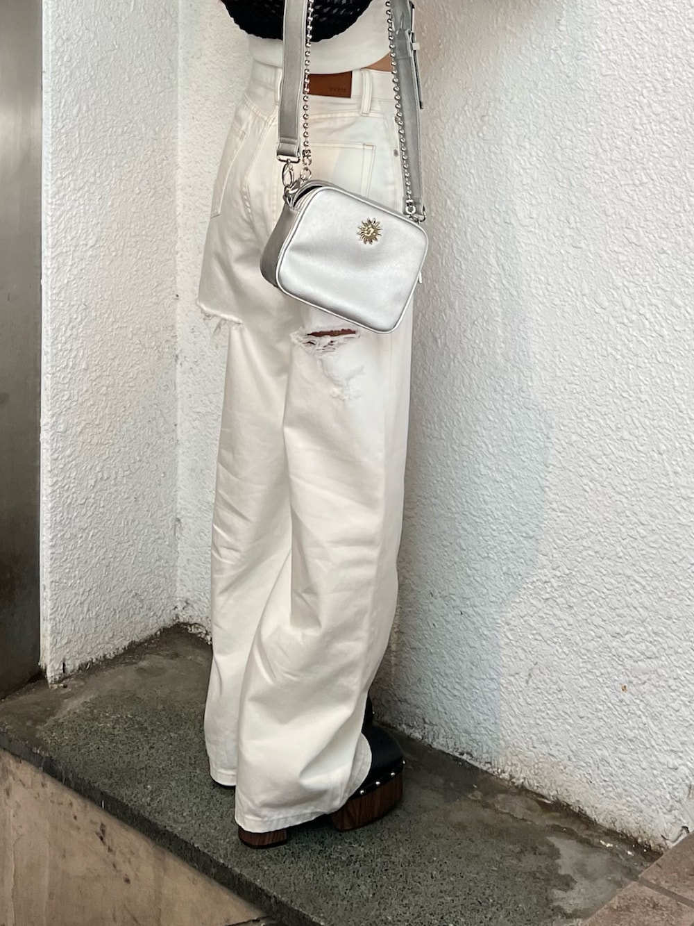 ホワイト系のデニムパンツ、ブラック系のサンダル、ブラック系のニット/セーターを着用したレディースの春コーディネートの5枚目の写真