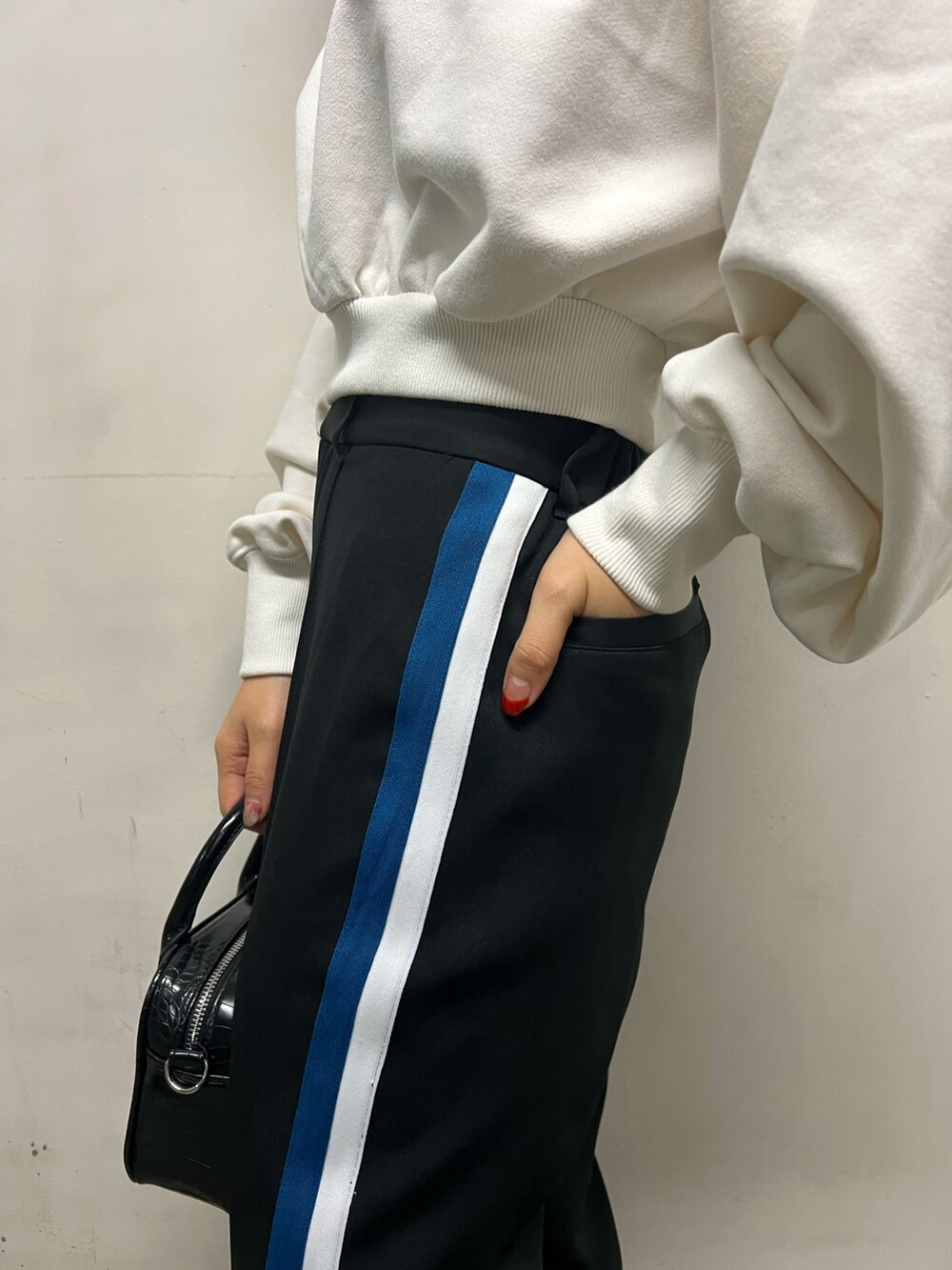 ブラック系のスラックス、ブラック系のショルダーバッグ、ホワイト系のスウェットを着用したレディースの冬コーディネートの6枚目の写真