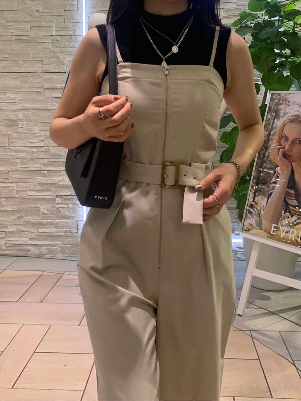 ブラック系のタンクトップ、ホワイト系のサロペット/オーバーオール、ブラック系のショルダーバッグを着用したレディースの夏コーディネートの6枚目の写真