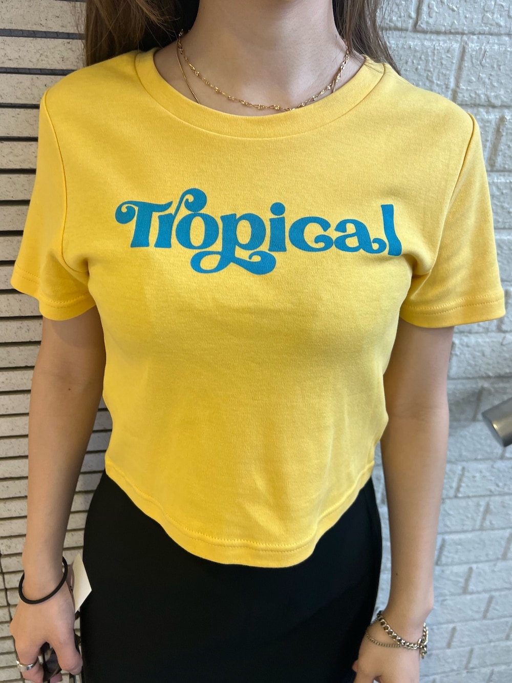 ブラック系のスカート、イエロー系のTシャツ/カットソー、ブラック系のサンダルを着用したレディースの春コーディネートの7枚目の写真