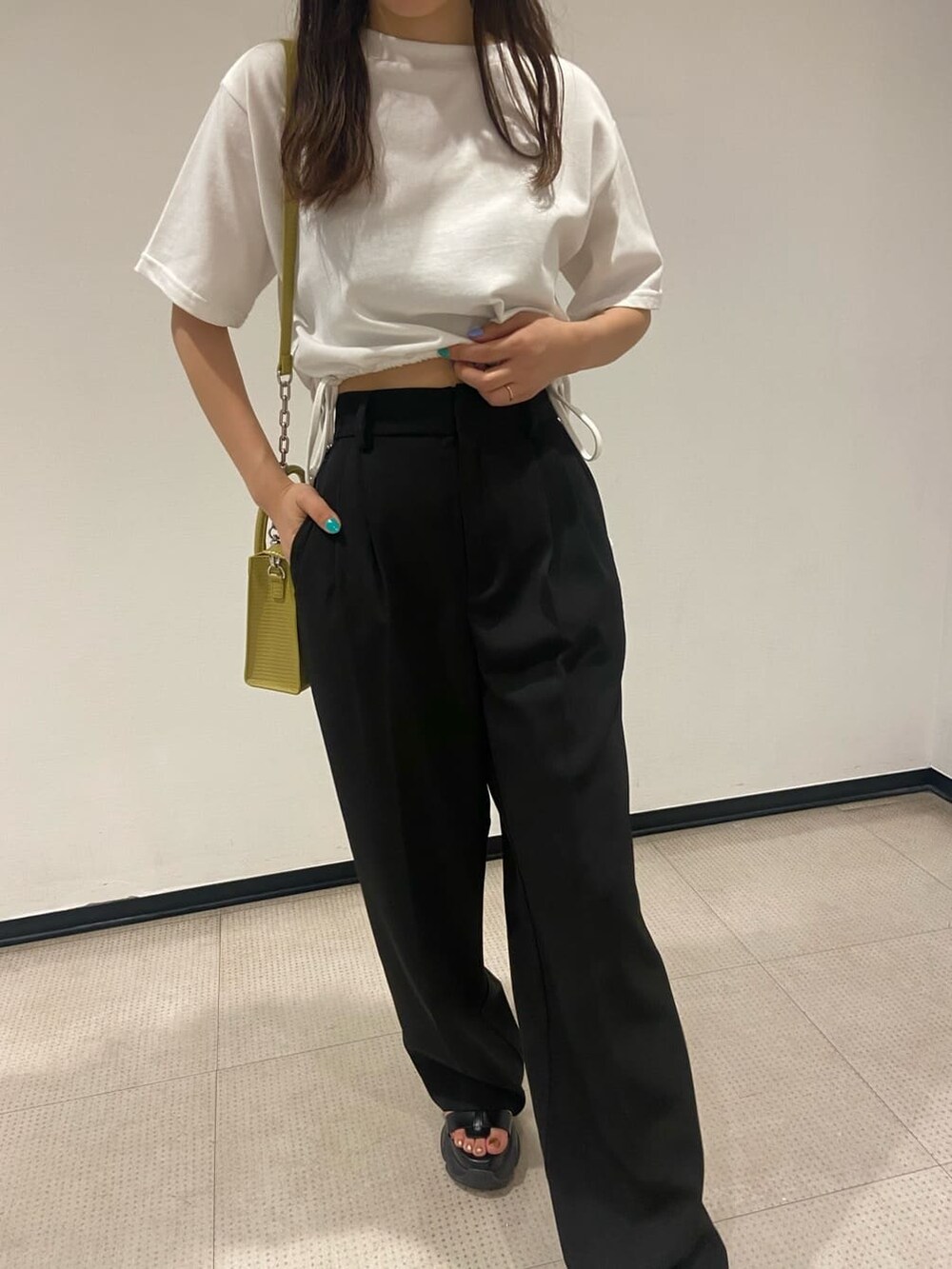 ブラック系のスラックス、ホワイト系のTシャツ/カットソー、イエロー系のショルダーバッグを着用したレディースの春コーディネートの4枚目の写真