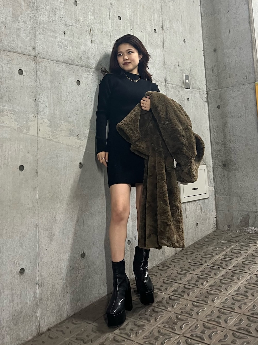 ブラック系のブーツ、ブラウン系のチェスターコート、ブラック系のワンピースを着用したレディースの冬コーディネートの5枚目の写真