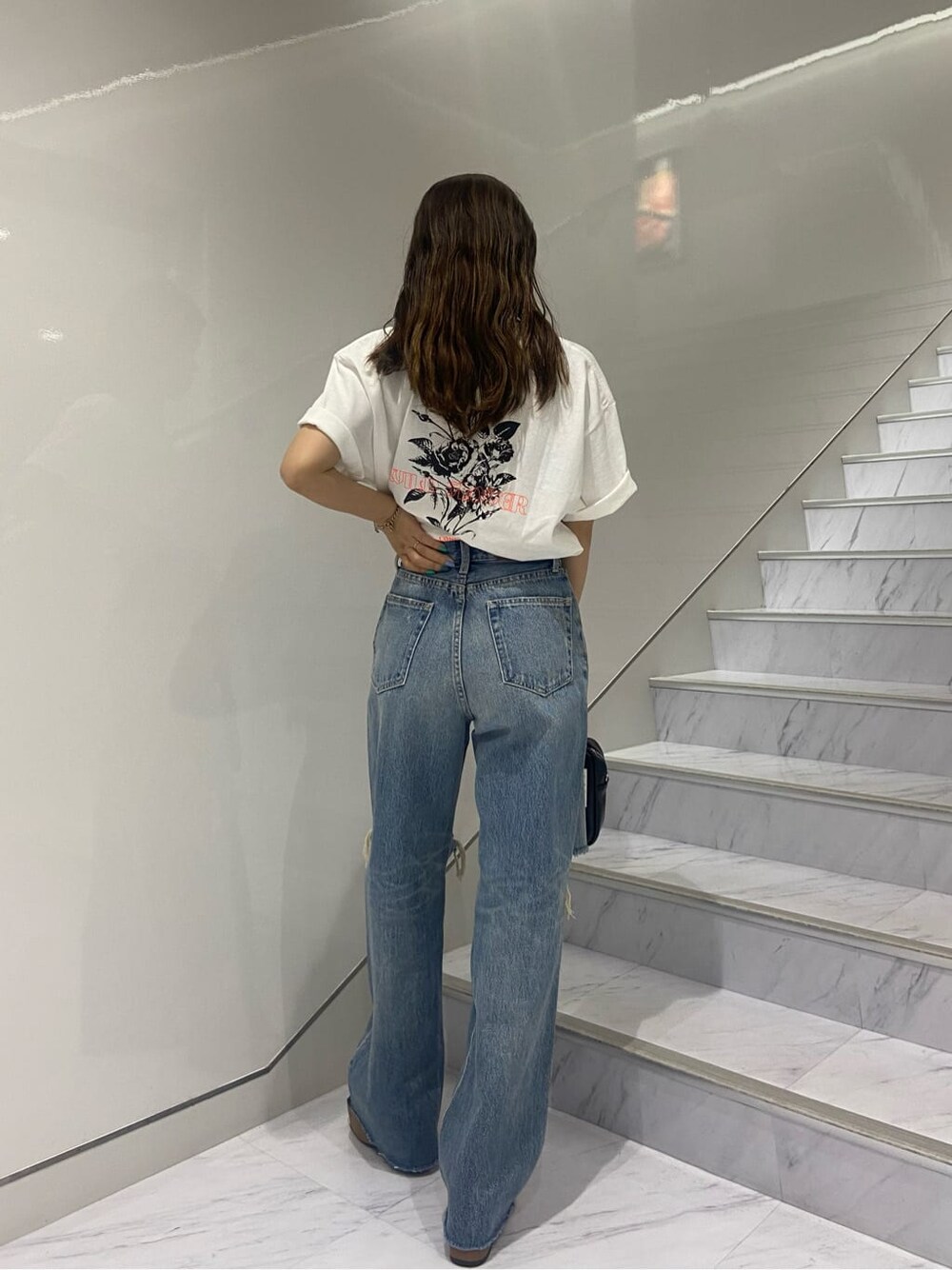 ブラック系のショルダーバッグ、ブラック系のサンダル、ブルー系のデニムパンツを着用したレディースの夏コーディネートの6枚目の写真