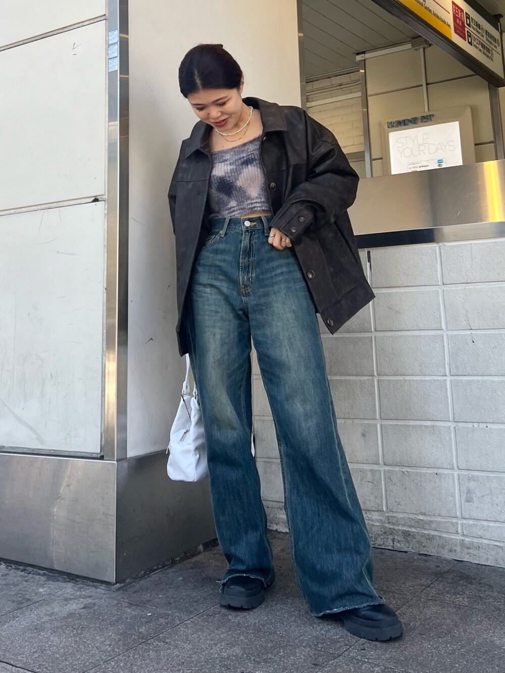 ブルー系のデニムパンツ、ホワイト系のハンドバッグ、ブラック系のブーツを着用したレディースの冬コーディネートの4枚目の写真