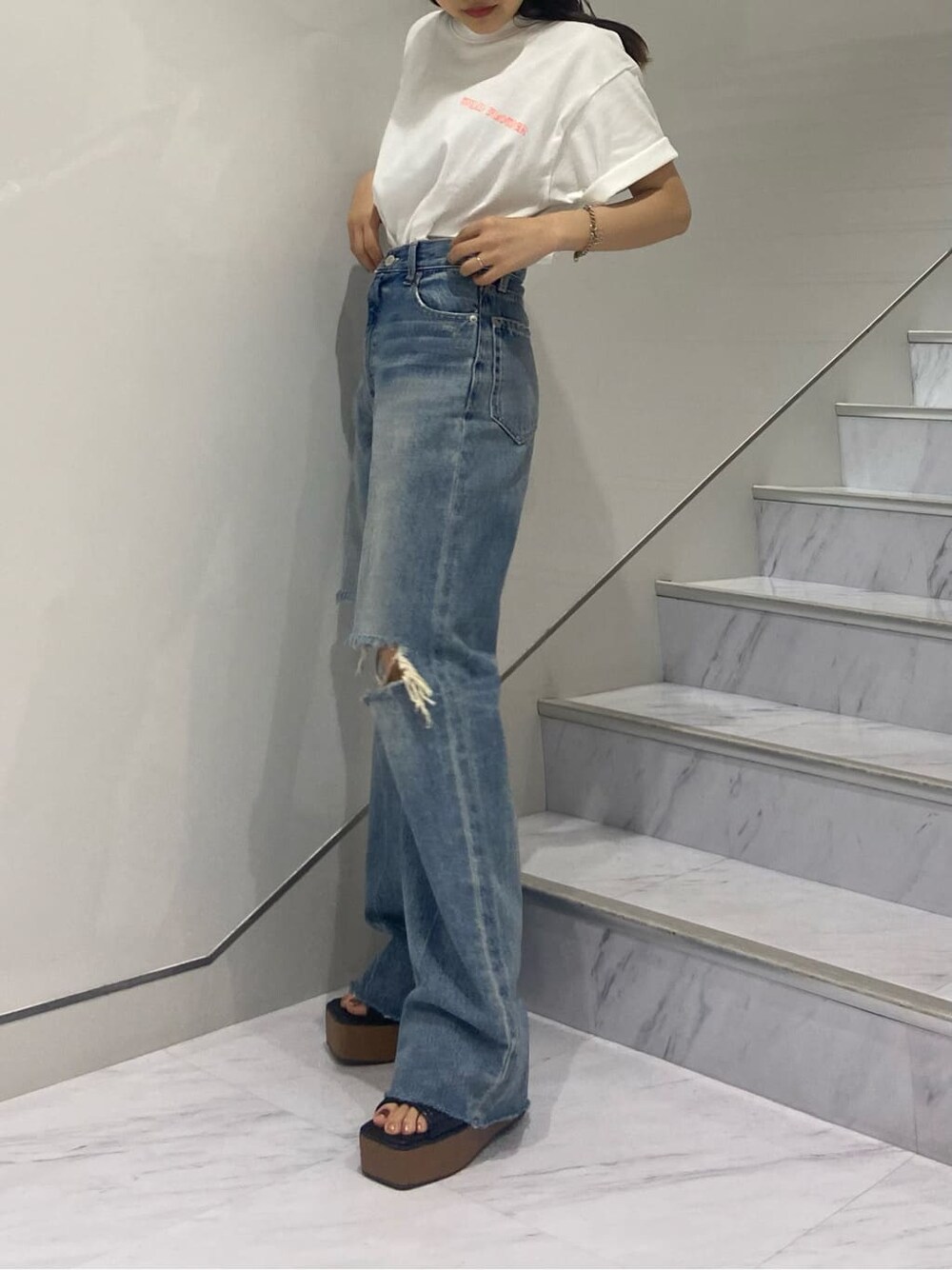 ブラック系のショルダーバッグ、ブラック系のサンダル、ブルー系のデニムパンツを着用したレディースの夏コーディネートの3枚目の写真