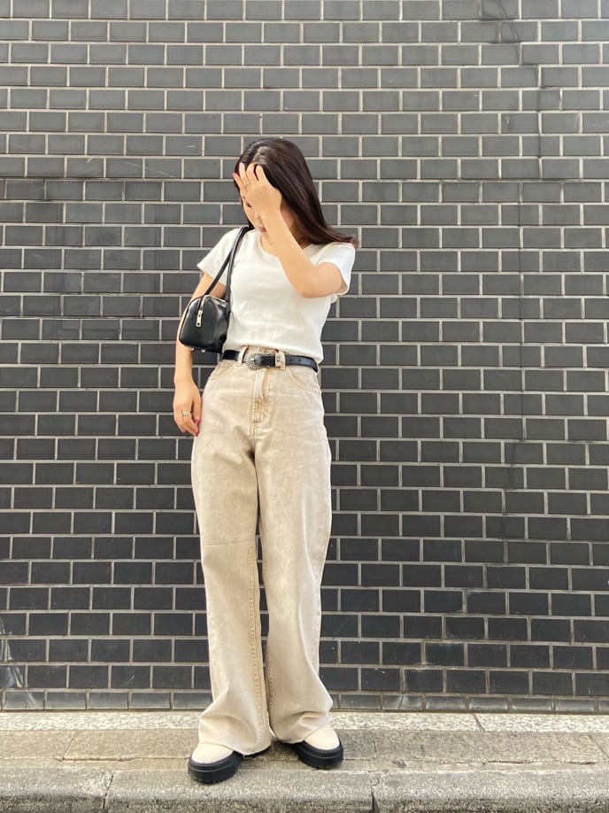 ブラック系のボストンバッグ、ベージュ系のTシャツ/カットソー、ベージュ系のデニムパンツを着用したレディースの春コーディネートの2枚目の写真